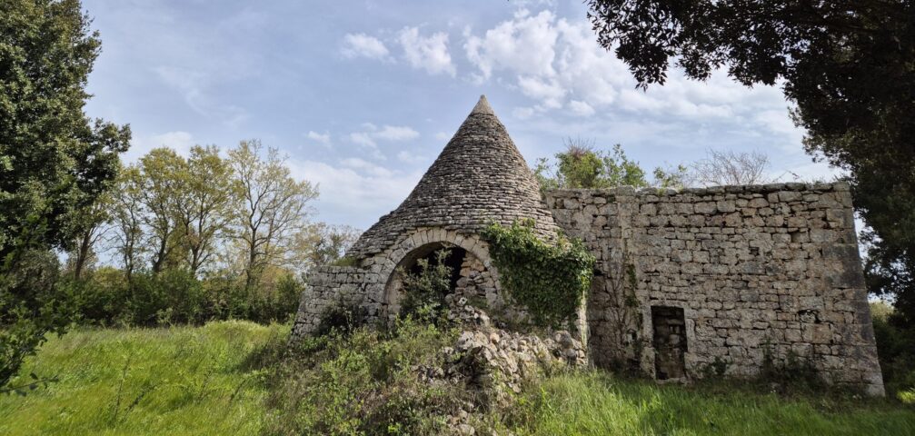 Le cône et son arche. Le cône du trullo et son arche en pierre, entourés de verdure