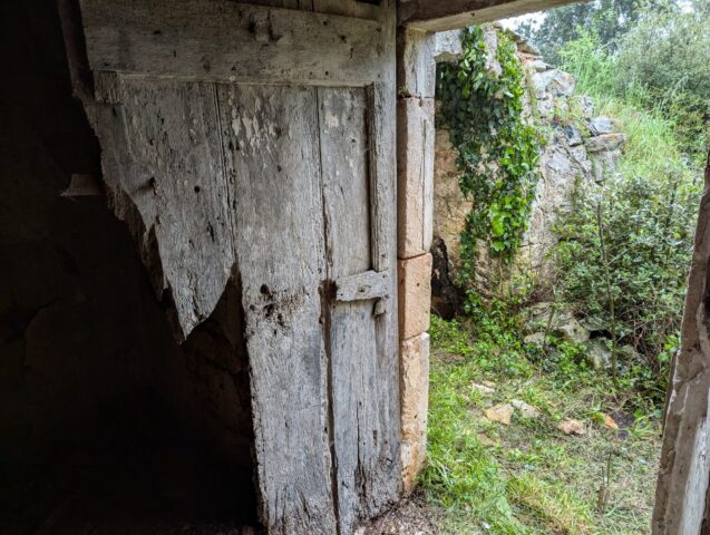 Une porte ancienne, à restaurer. Porte ancienne en bois écaillé dans un mur de pierre